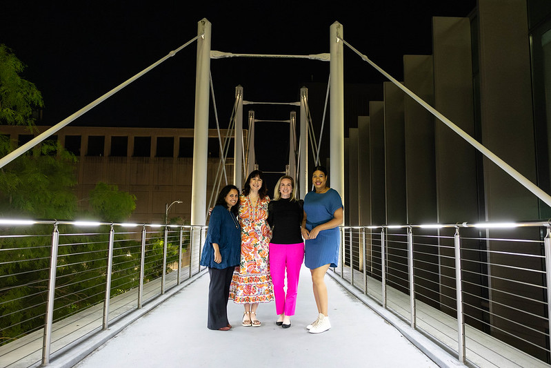 Four women standing on a bridge